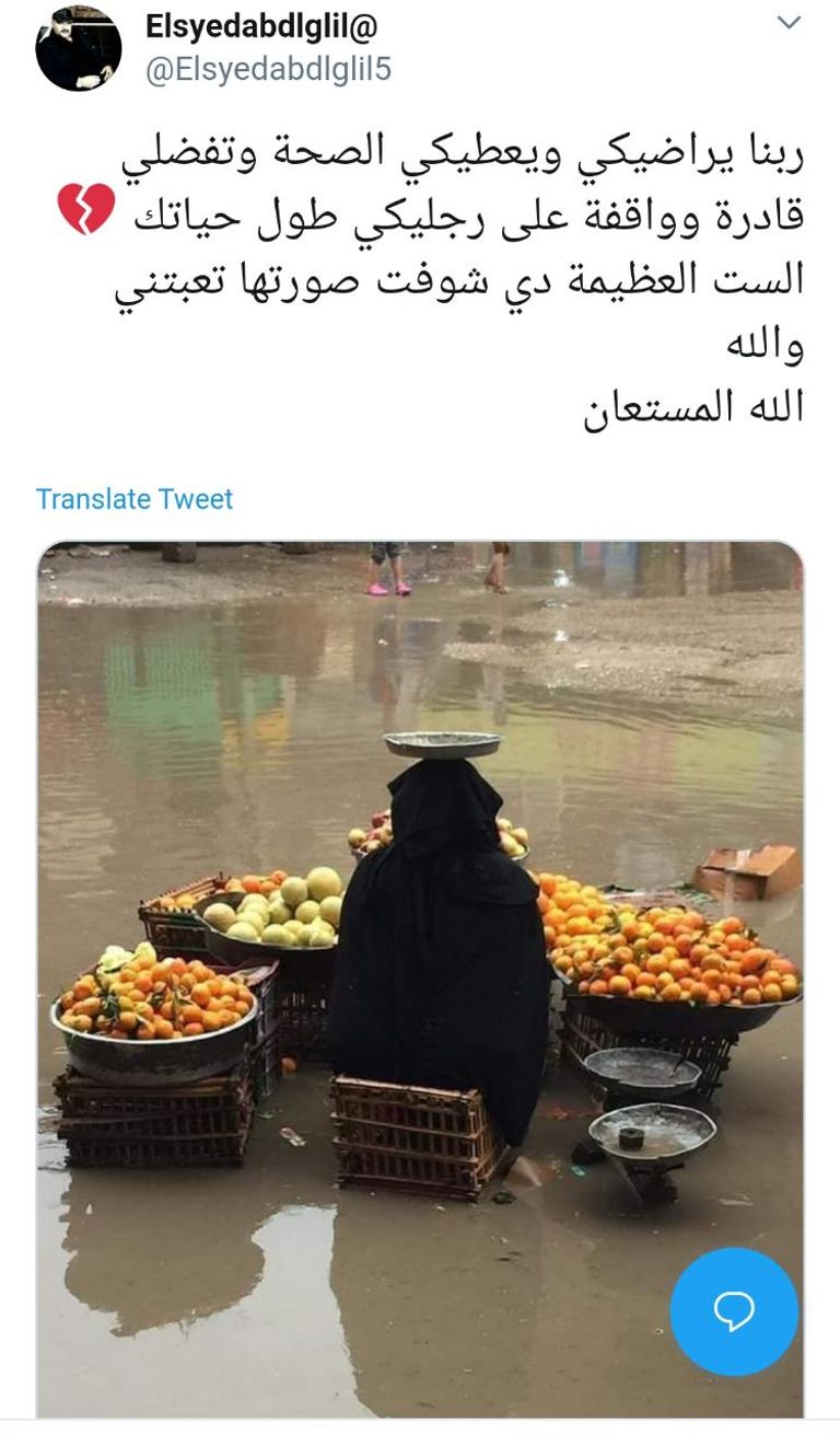 مسنة تبيع الفاكهة وسط هطول الأمطار بمصر