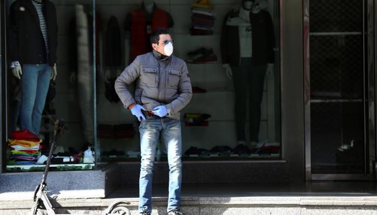 أسباني يرتدي كمامة يقف أمام محل ملابس مغلق في مدريد