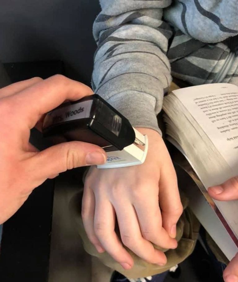 معلمة تضع ختمها على أيدي الطلاب لتشجيعهم على غسلها