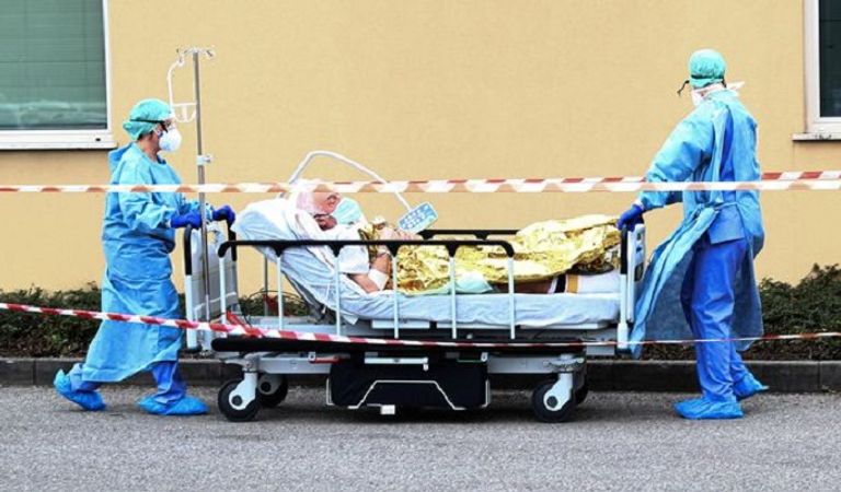 ممرضون يرتدون الزي العازل أثناء نقل أحد المرضى في مستشفى طبيب يقف أمام خيمة الفرز أقيمت أمام مستشفى إيطالي