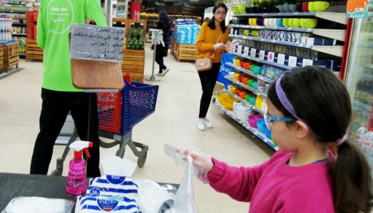 فتاة مصرية تعقم يديها قبل التسوق بمتجر