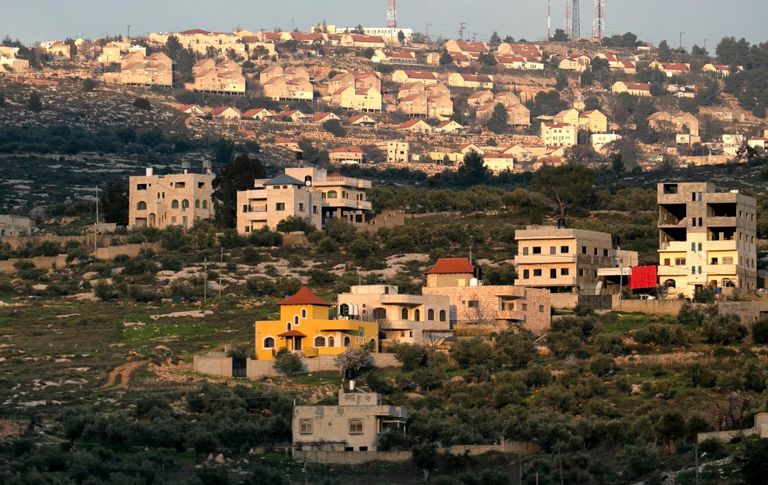 جندي إسرائيلي يصوب سلاحه نحو مسن فلسطيني