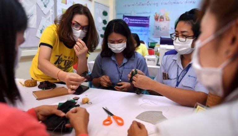 تايلانديات يتعلمن كيفية صناعة الكمامات