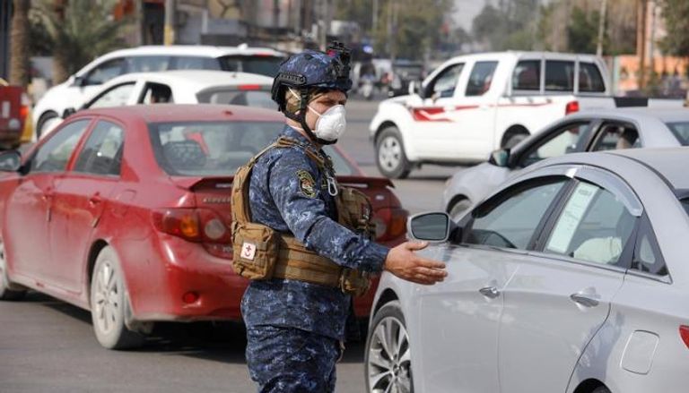 رجل أمن عراقي يرتدي الكمامة في أحد شوارع بغداد