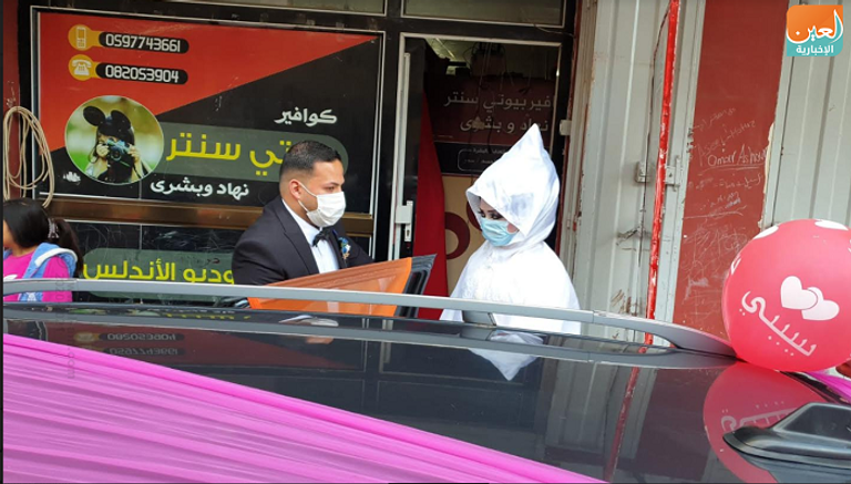 العريس والعروس أمام صالون التجميل في قطاع غزة ويرتديان الكمامة للوقاية من فيروس كورونا الجديد عروسان يرتديان الأقنعة الطبية في قطاع غزة للوقاية من كورونا