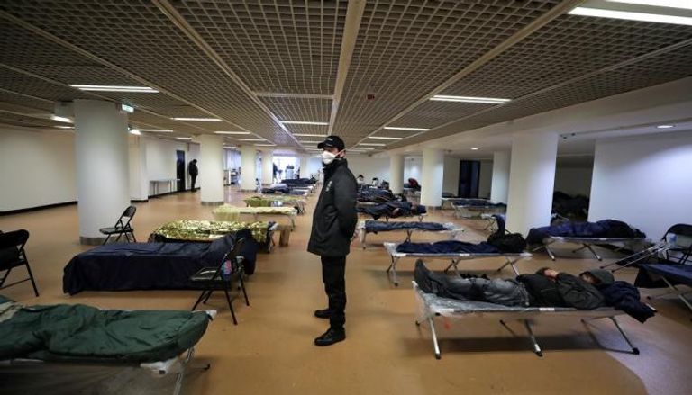 حارس أمن يرتدي كمامة داخل مأوى للمشردين في فرنسا