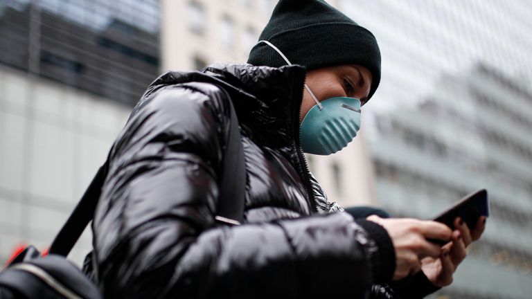 فتاة ترتدي كمامة للوقاية من فيروس كورونا وتحمل هاتفها الذكي الهاتف المحمول مصدر خطير لعدوى كورونا