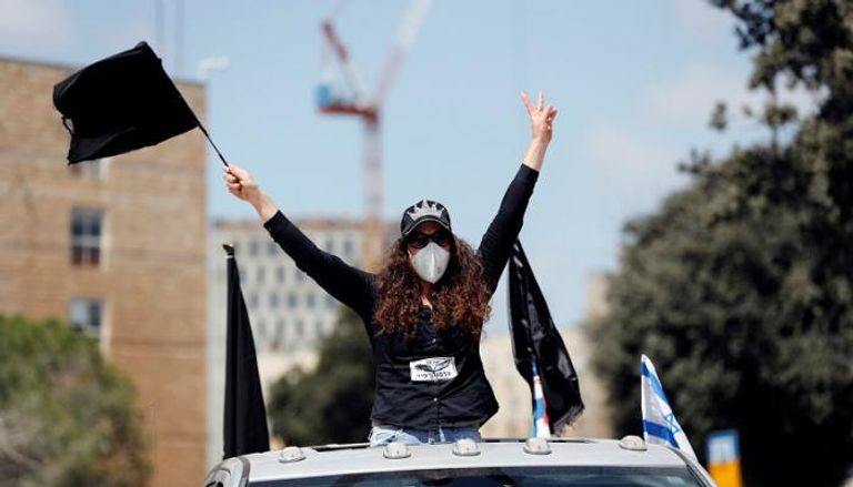 إسرائيلية ترتدي الكمامة خلال مشاركتها بمسيرة احتجاجية ضد رئيس الوزراء الإسرائيلي بنيامين نتنياهو
