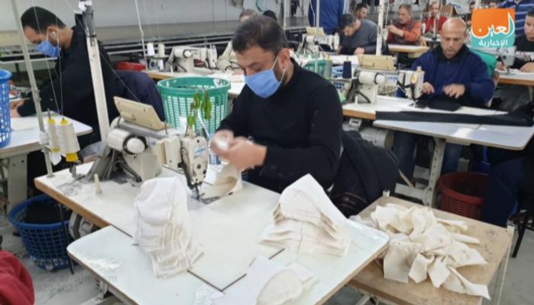 عمال يصنعون الكمامات في مصنع شركة 