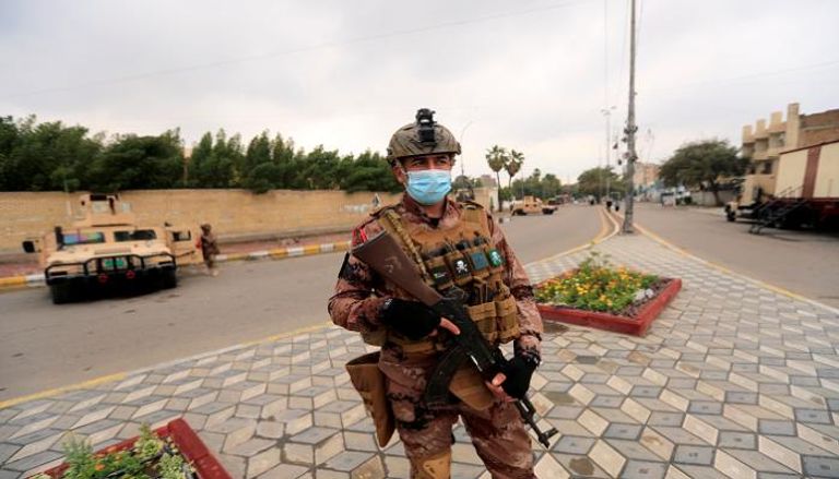 جندي عراقي يرتدي كمامة أثناء تنفيذ حظر التجوال