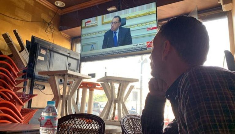 مواطن يتابع خطابا لرئيس الوزراء داخل مقهى