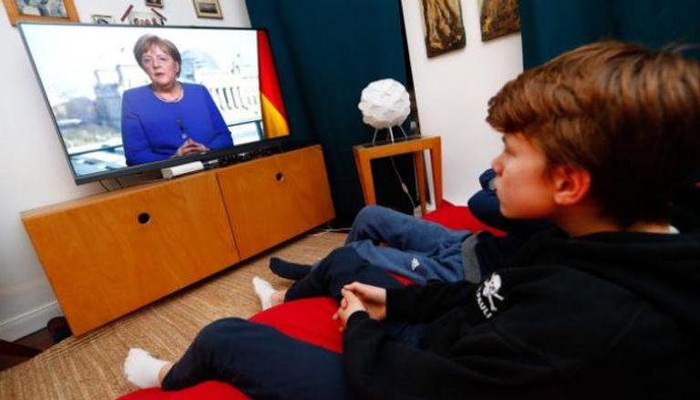 ألمان يتابعون كلمة لميركل عبر شاشات التلفزيون