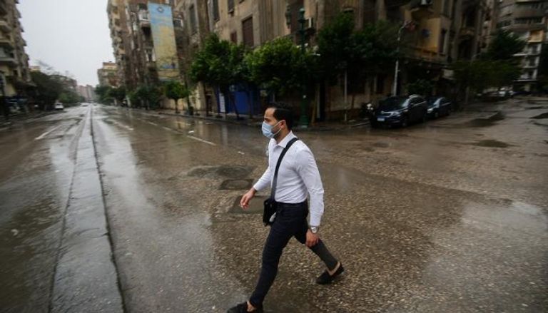 شاب مصري يرتدي الكمامة في أحد شوارع القاهرة خلال فترة حظر التجول لاحتواء فيروس كورونا