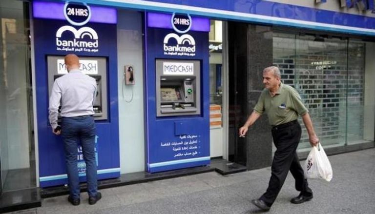 لبناني يحاول سحب نقود من مكينة بنك مغلق في بيروت - رويترز
