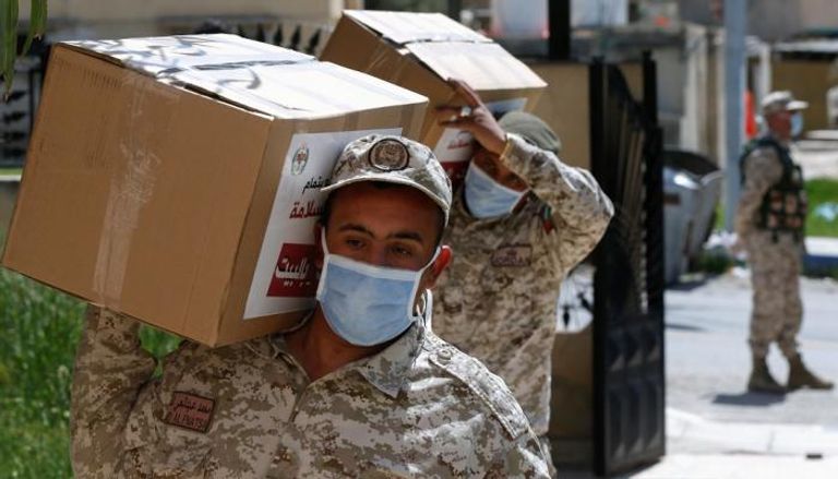 جنود يحملون طرودًا غذائية لتوزيعها على بعض سكان مدينة الزرقاء
