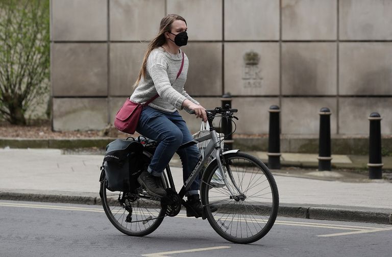 فتاة تستقل دراجة وترتدي كمامة للوقاية من فيروس كورونا الجديد