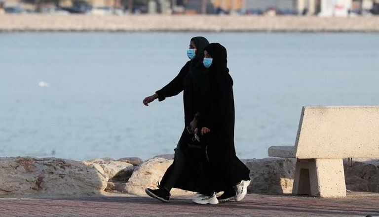 فتاتان ترتديان كمامات خلال المشي قرب الشاطئ في القطيف 