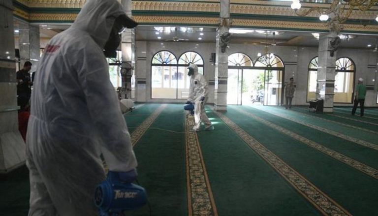 عمال يرشون مسجدا بالمطهرات