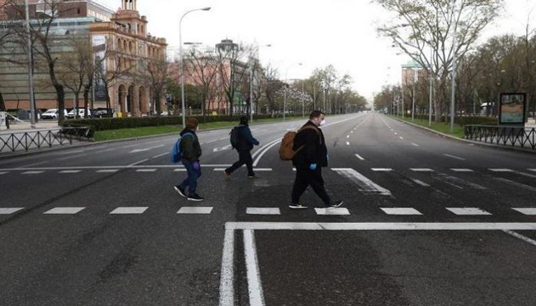 أشخاص يضعون كمامات واقية يسيرون في العاصمة الإسبانية مدريد - رويترز