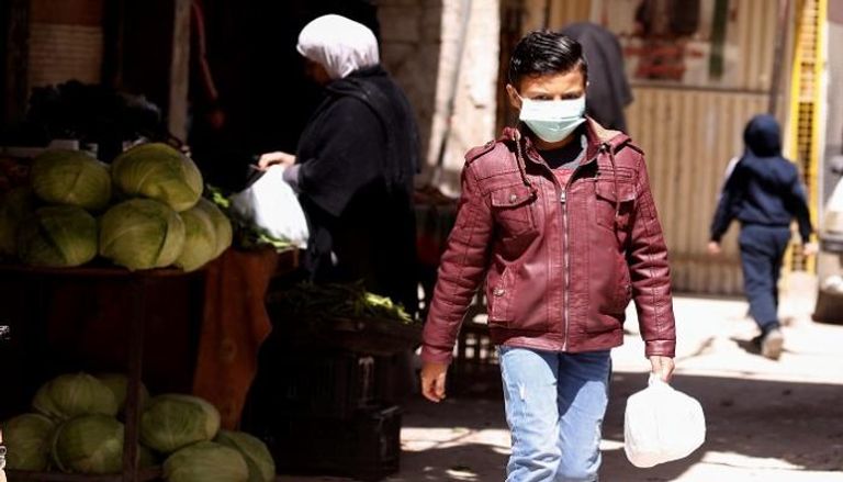 صبي يرتدي كمامة للوقاية من عدوى كورونا في سوريا