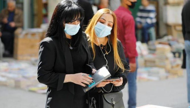 سيدتان ترتديان كمامتين للوقاية من فيروس كورونا في العراق