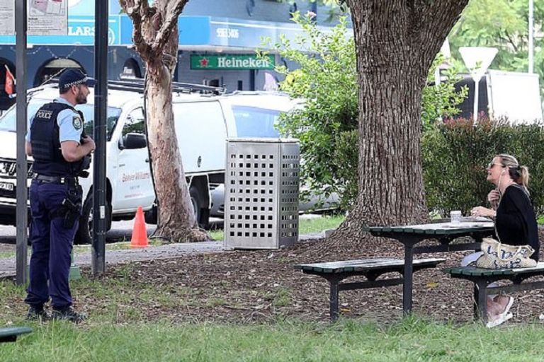 سيدة تجلس على أحد المقاعد وضابط يطلب منها المغادرة ضابط يطلب من سيدة الرحيل رغم جلوسها بمفردها - ديلي ميل