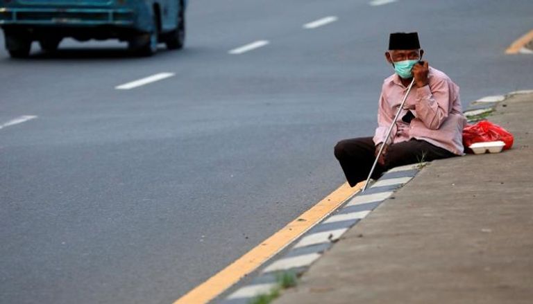 مسن يرتدي كمامة للوقاية من عدوى كورونا في إندونيسيا