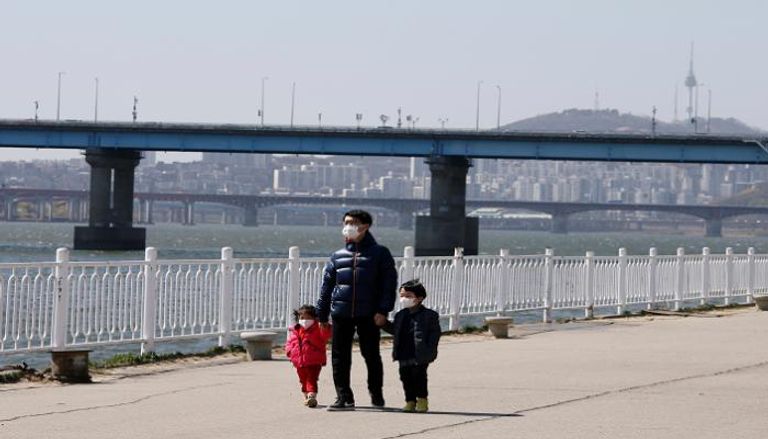 رجل يتجول برفقة أولاده في أحد شوارع كوريا الجنوبية