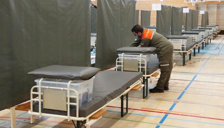 عامل من الدفاع المدني يعد سريراً داخل مركز طبي في سويسرا 