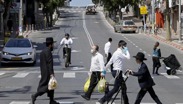 أشخاص يرتدون الكمامات في شوارع إسرائيل