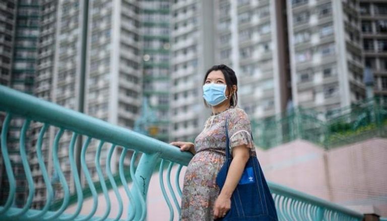 صورة لإحدى السيدات الحوامل في هونج كونج ترتدي القناع الطبي
