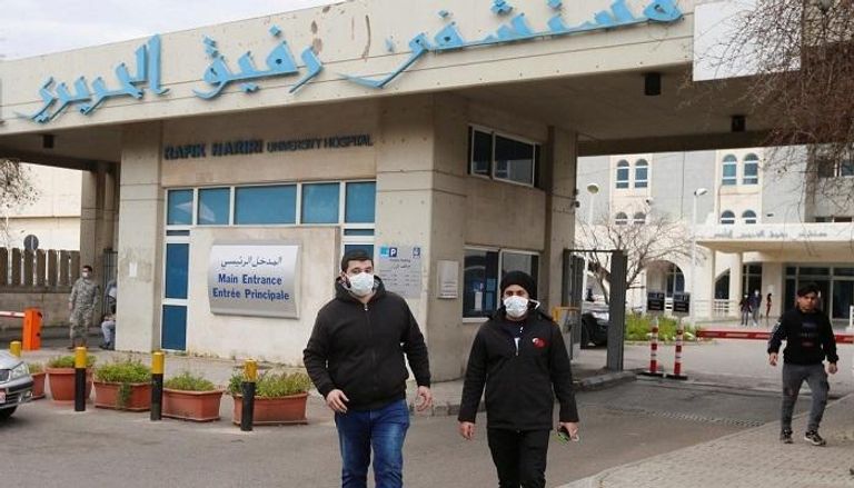 شخصان يرتديان الكمامات أمام مستشفى رفيق الحريري في لبنان 