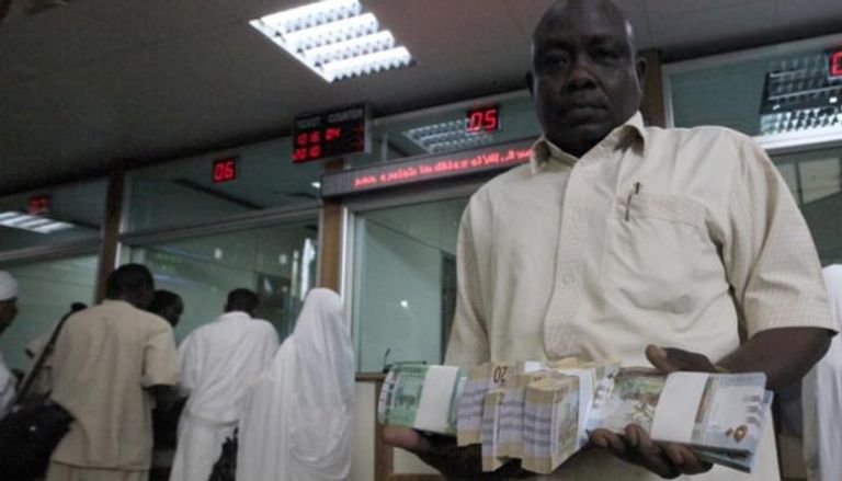 مواطن يمسك بعملات ورقية من الجنيه السوداني في أحد البنوك