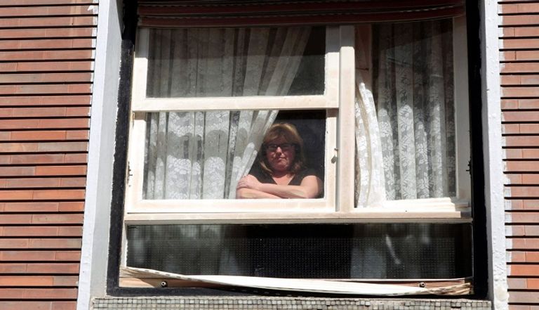 امرأة تقف في شرفة منزليها للاستمتاع بالشمس نصائح للحفاظ على نظرك خلال العزل المنزلي