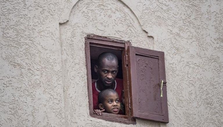 مغربي وابنه يتابعان من نافذة المنزل عمليات تطهير شارع في العاصمة الرباط
