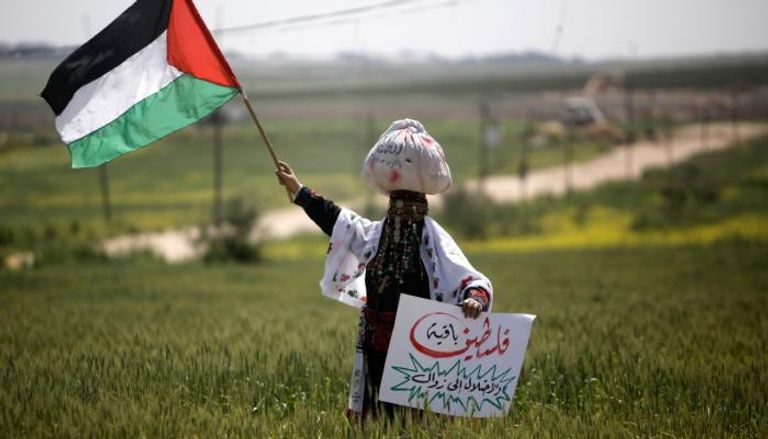 فلسطينية ترفع علم بلادها