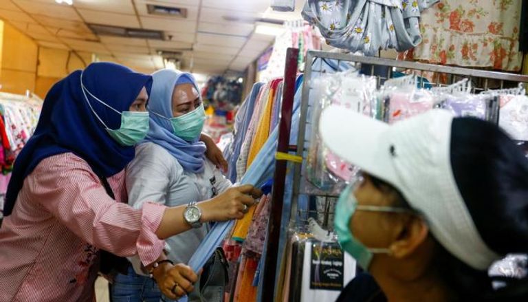 نساء يرتدين أقنعة واقية في سوق بإندونيسيا 