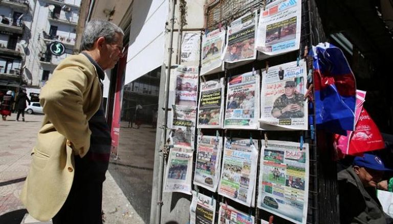 جزائري أمام مجموعة من الصحف اليومية المحلية