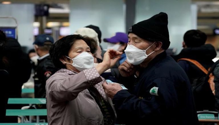 سيدة تساعد زوجها في ارتداء الكمامة بكوريا الجنوبية