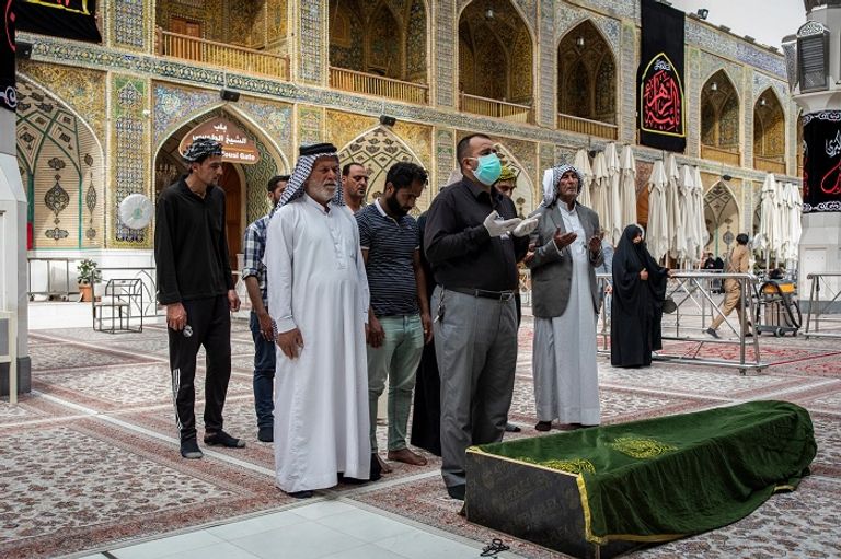 جانب من صلاة الجنازة على أحد المتوفين أمام ضريح الإمام علي في النجف الدفاع المدني العراقي يعقم أحد المنشآت - نيويورك تايمز