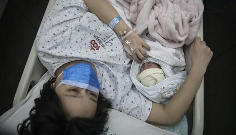 سيدة تضع كمامة بعد ولادتها طفلا بأحد المستشفيات