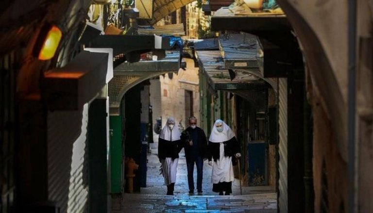3 أشخاص يرتدون الكمامات في أحد شوارع القدس