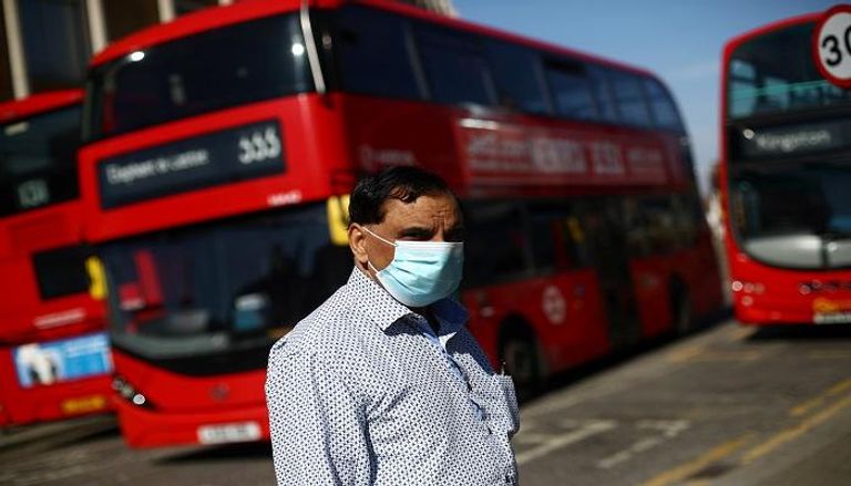 رجل يرتدي كمامة أمام محطة حافلات في لندن
