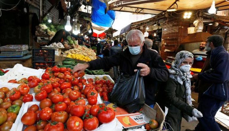رجل يرتدي قناع وجه أثناء شرائه الخضراوات في عمان