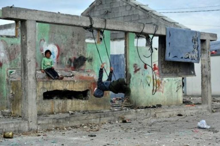 سيدة من غجر الروما أمام سلة مهملات تتكدس فيها القناني البلاستيكية