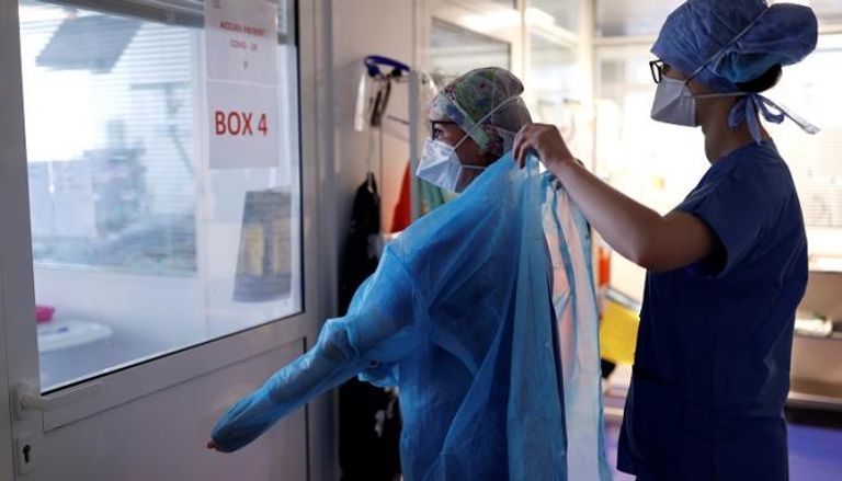 ممرضة تساعد طبيبة في ارتداء ملابسها الوقائية قبل التعامل مع مريض بفيروس كورونا