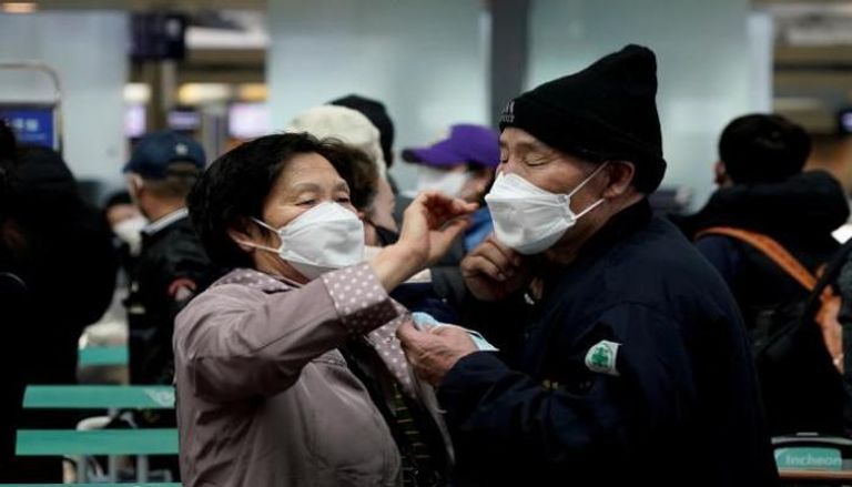 سيدة تساعد زوجها على ارتداء الكمامة بكوريا الجنوبية - أرشيفية