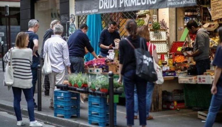 فرنسيون يصطفون أمام متجر للفاكهة والخضر في باريس