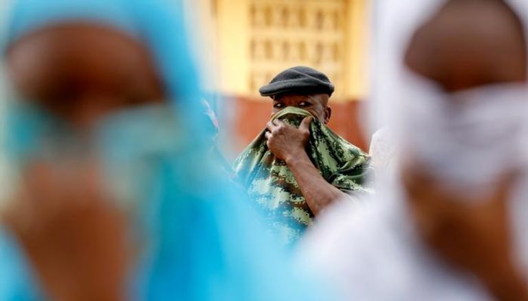 رجل يغطي وجهه بقميصه للوقاية من كورونا في غانا
