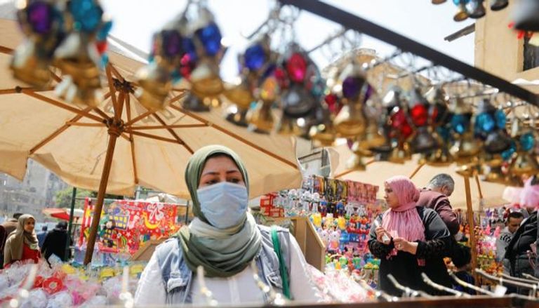 امرأة ترتدي كمامة في سوق لفوانيس رمضان بمصر
